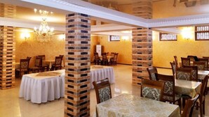 A dining area with brick pillars, round tables, and chairs. - Euro-asia (Khiva)
