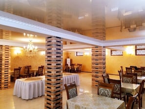 A dining area with brick pillars, round tables, and chairs. - Euro-asia (Khiva)