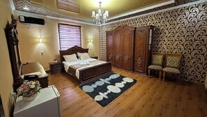 A bedroom with a bed, a dresser, a chair, a desk, and a chandelier. - Euro-asia (Khiva)