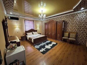 A bedroom with a bed, a dresser, a chair, a desk, and a chandelier. - Euro-asia (Khiva)