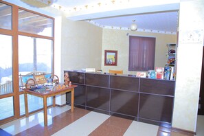 A reception area with a reception desk, a window with a view, a reception sign, and a shelf with books and a globe. - Euro-asia (Khiva)