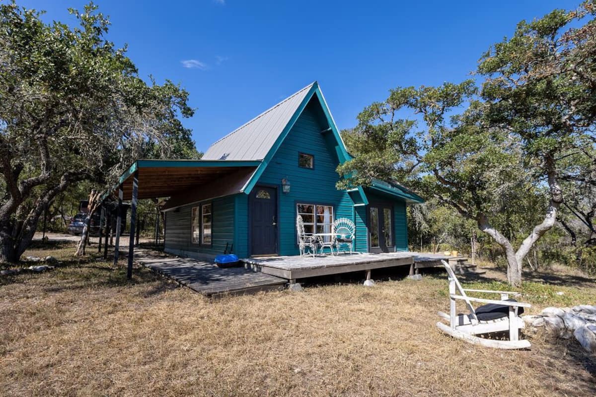A blue house with a porch, a small deck, and a rocking chair.