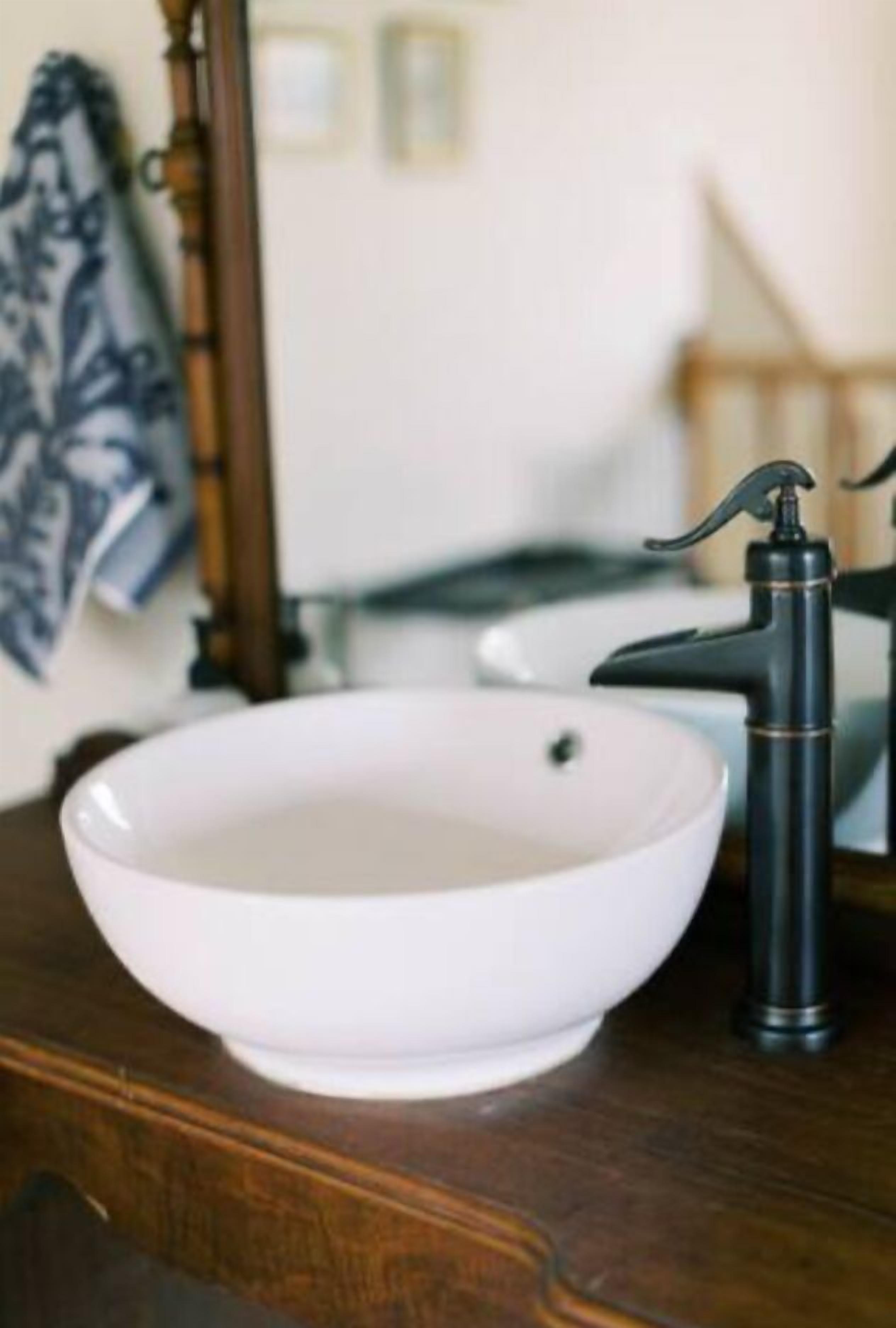 A white basin with a black faucet on a wooden surface.