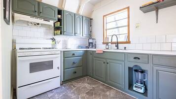 A kitchen with a stove, oven, sink, and a built-in blender.