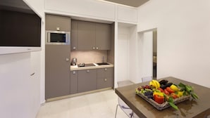 Une cuisine moderne avec des meubles gris, un four à micro-ondes et un évier. On peut voir un panier de fruits sur le plan de travail.