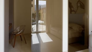 Une chambre moderne dotée d’une porte coulissante en verre donnant sur un balcon, d’une chaise et d’un lit.