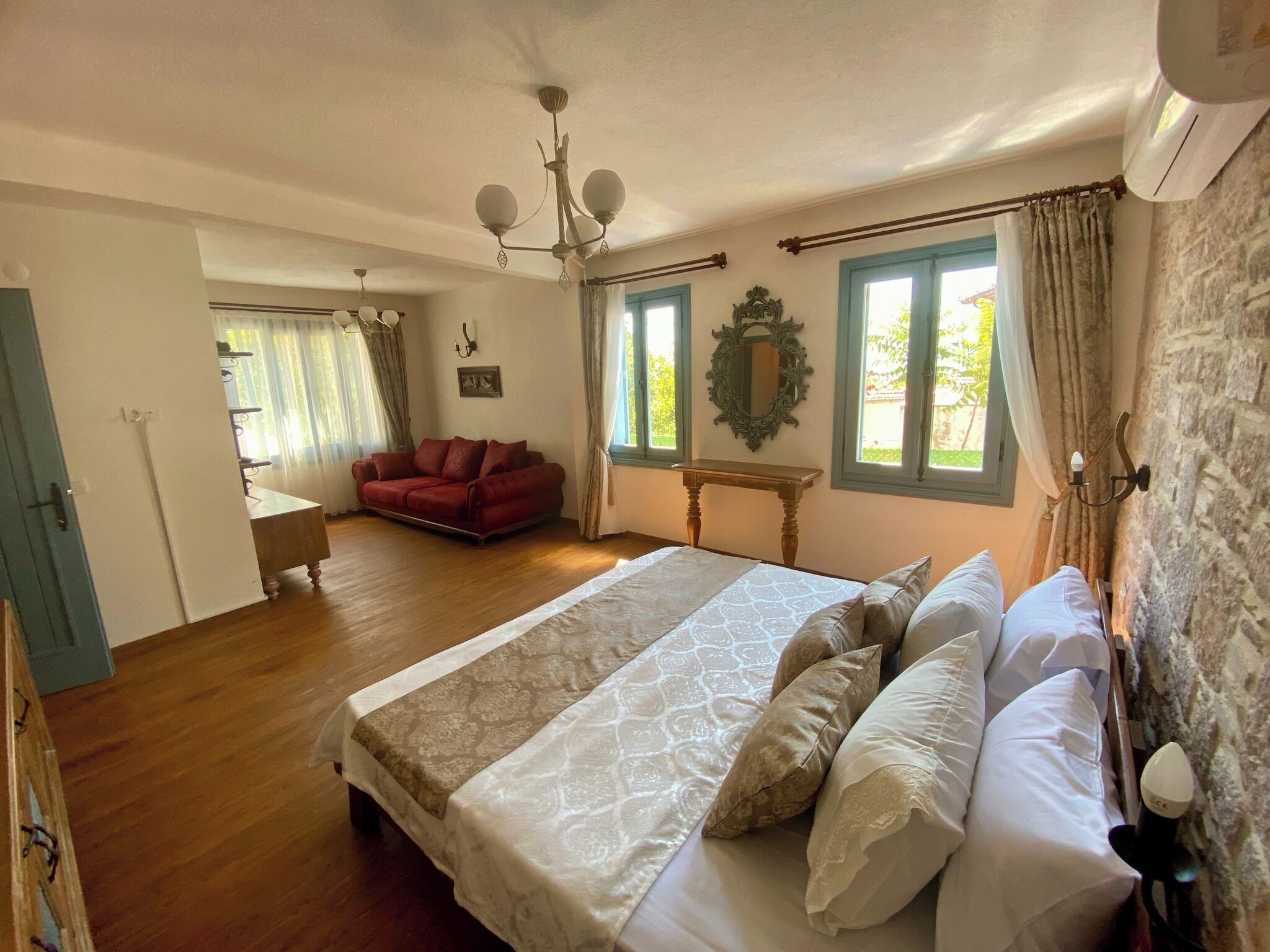 Ein Schlafzimmer mit einem großen Bett, einem roten Sofa, einem Holztisch und einer Chandelüster.