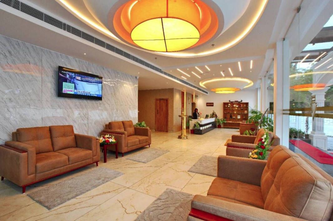 Um hall com sofás, um balcão de recepção e um grande lustre.