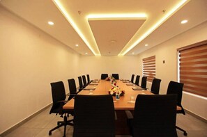 A conference room with a long table, black chairs, and a ceiling light fixture. - Veliyil Castles (Cherthala)