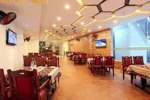 A restaurant with hexagonal ceiling lights, wooden tables, and chairs. - Veliyil Castles (Cherthala)