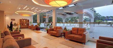A spacious lobby with comfortable seating, a reception desk, and large windows offering a view of the outdoors.