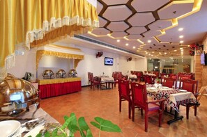 Restaurante com design de teto hexagonal, várias mesas de jantar e uma área de buffet.