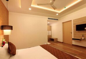 A modern hotel room with a bed, a ceiling fan, a TV, and a wooden floor. - Veliyil Castles (Cherthala)