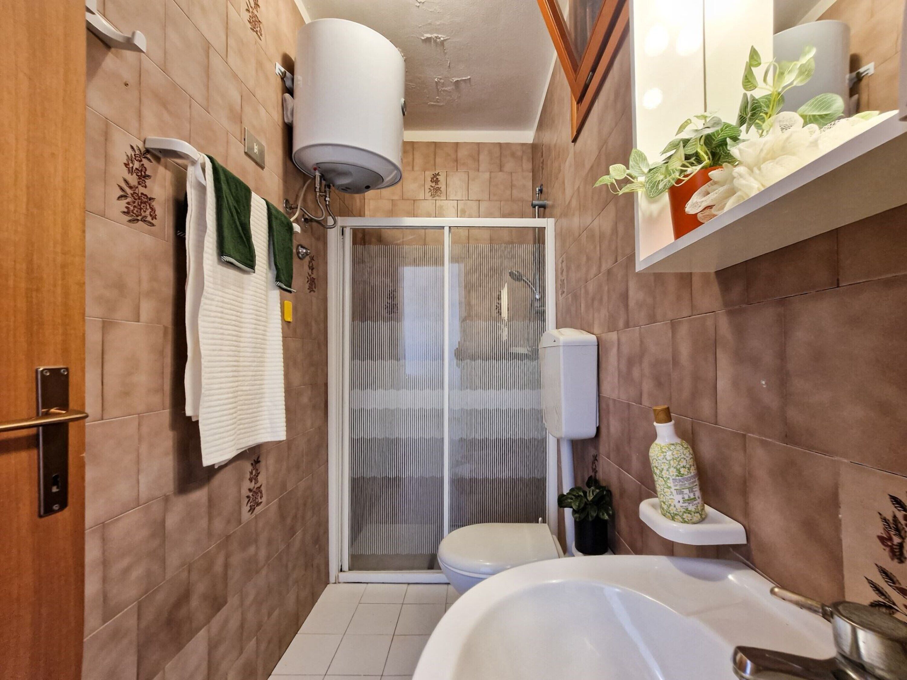 Une salle de bain avec douche, toilettes et lavabo.