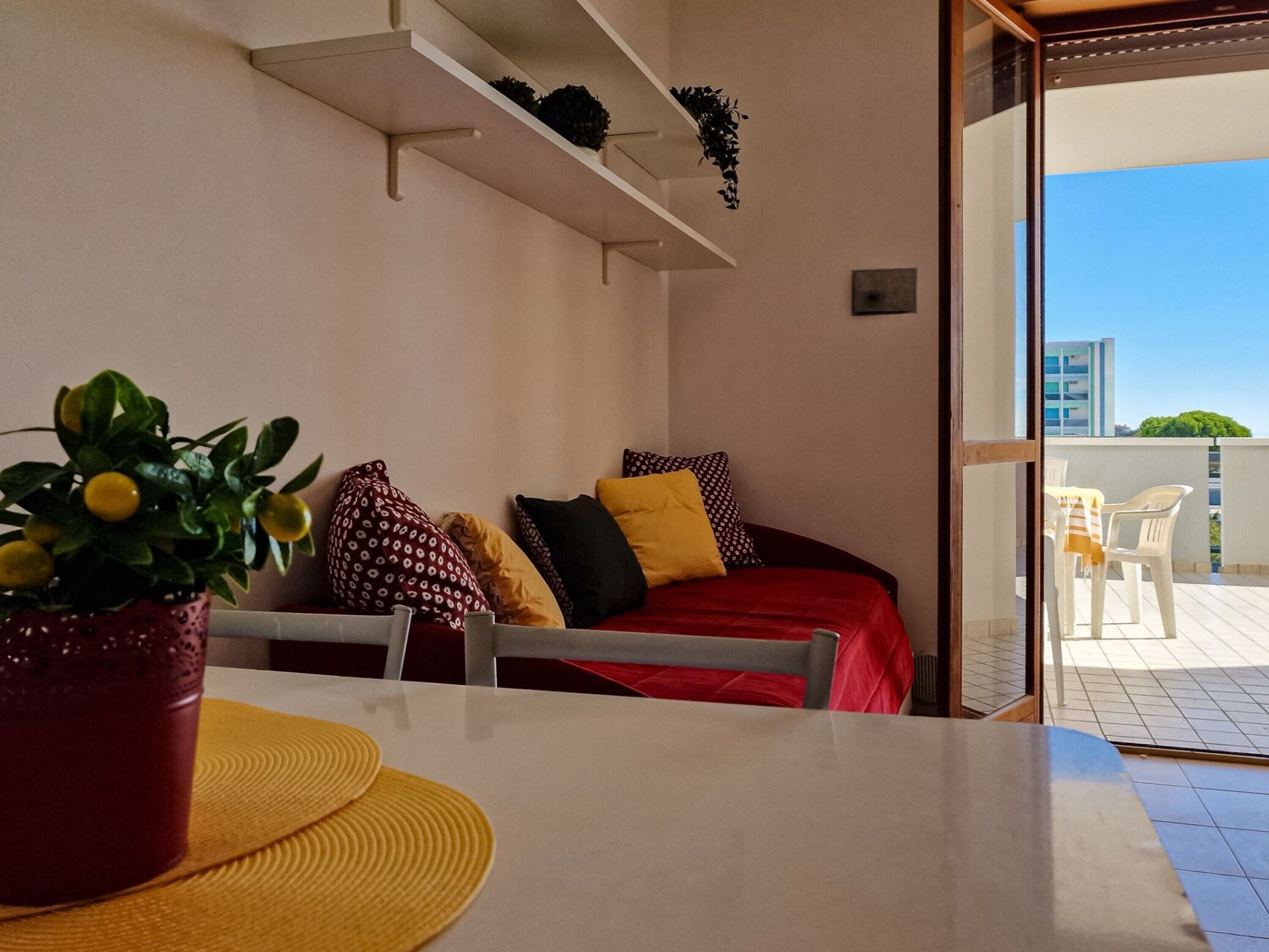 Une chambre avec un lit, une table ornée d’une plante et une vue sur l’extérieur.