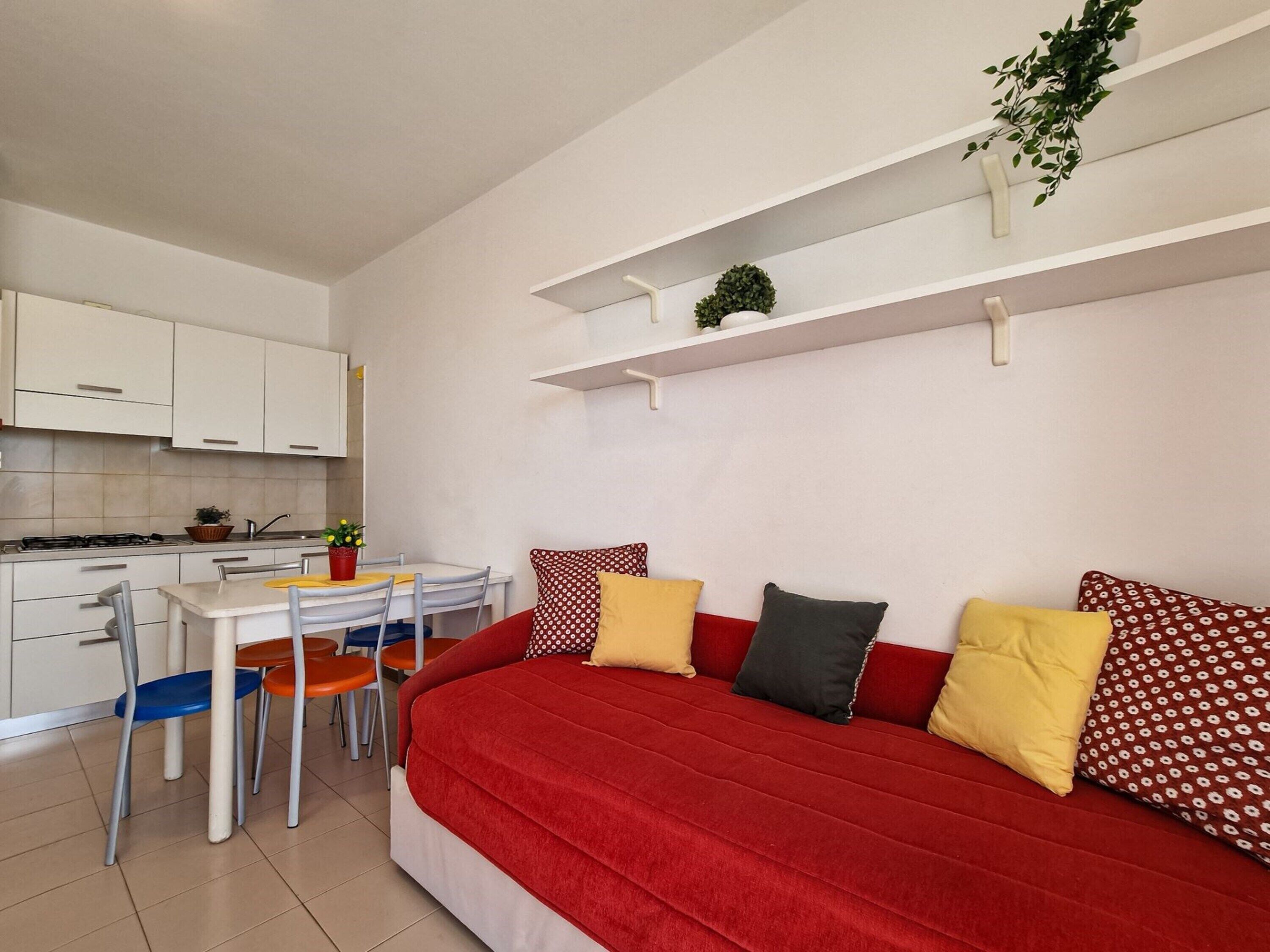 A compact living space with a kitchenette, a dining area, and a sofa with multiple cushions.