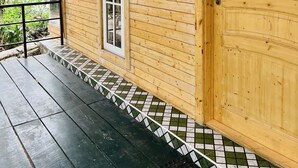 Fachada de madera con una puerta grande, una ventana y piso de baldosas.