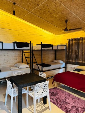 A compact room with bunk beds, a dining table with chairs, and a ceiling fan.