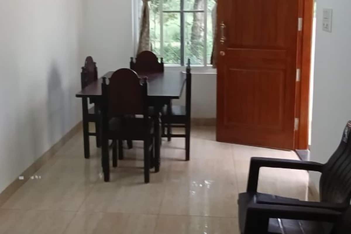 A dining area with a table and chairs, a ceiling fan, a window with curtains, and a wooden door.