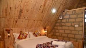 Una habitación con paneles de madera, una cama, una pared de piedra y techo de madera.