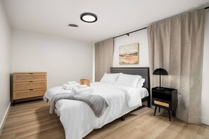 A modern bedroom with a bed, bedside table, and a wall-mounted painting. - The Silo 5- 1 BD Urban Haven (Morton)