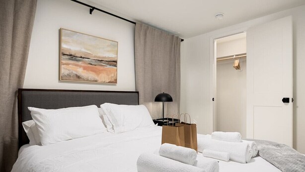 A neatly made bed with white linens, a brown paper bag, and rolled towels on a hotel room. - The Silo 5- 1 BD Urban Haven (Morton)