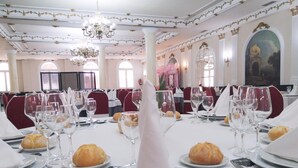 A formal dining room with white tables, red chairs, and a chandelier. - Hotel Florida (Albacete)