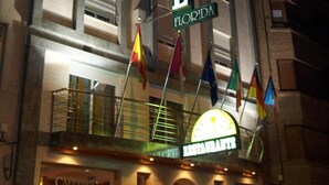 Un hôtel avec une enseigne bien visible indiquant « HÔTEL FLORIDA » et, en dessous, une enseigne pour le restaurant.