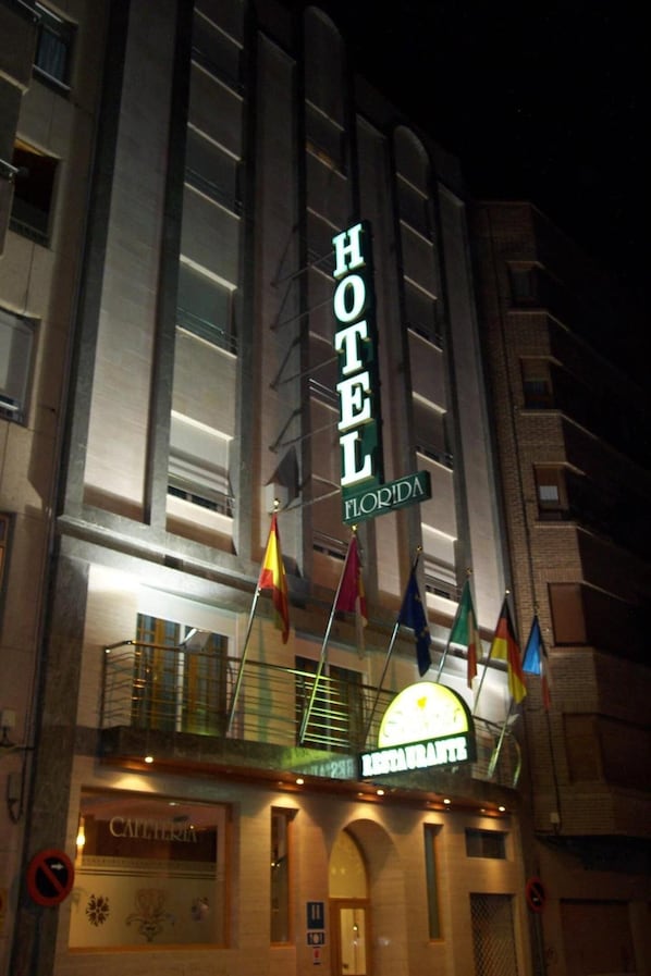 Un hôtel avec une enseigne bien visible indiquant « HÔTEL FLORIDA » et, en dessous, une enseigne pour le restaurant.