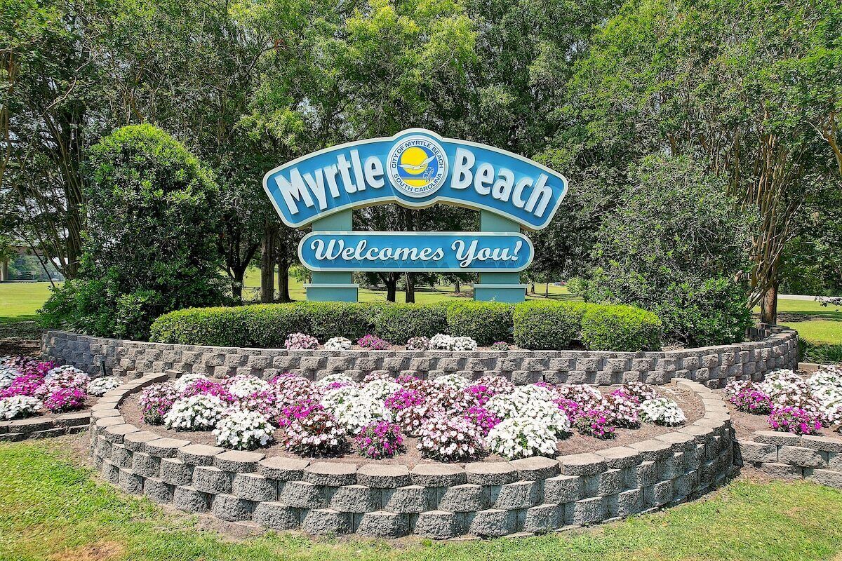 Een bord dat bezoekers verwelkomt in Myrtle Beach, met een aangelegde tuin ervoor.