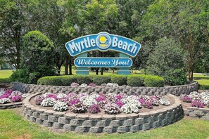 A sign welcoming visitors to Myrtle Beach with a landscaped garden in front.