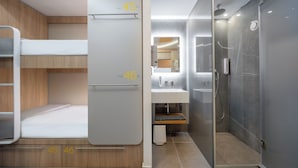 A modern hotel room with bunk beds, a bathroom with a glass shower enclosure, and a sink. - Epavli City Hostel (Chania)