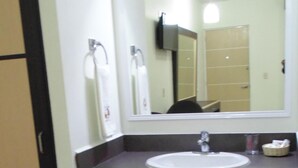 Un baño con un lavabo blanco, encimera oscura y un espejo encima.