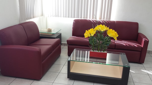 Una sala de estar con dos sofás rojos, una mesa de centro de vidrio y un jarrón con flores amarillas.