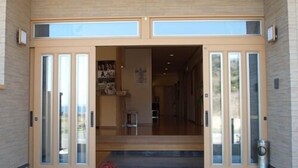 A modern building entrance with glass doors, a wooden ceiling, and a visible interior space. - Akatsukien (Kitaibaraki)