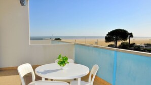 A balcony with a white table and chairs, a potted plant, and a view of the beach. - One Bedroom Coastal Flat - Beahost (San Michele al Tagliamento)