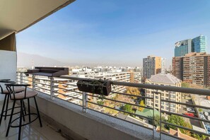 A balcony with a view of a cityscape, including high-rise buildings and a mountain in the distance.