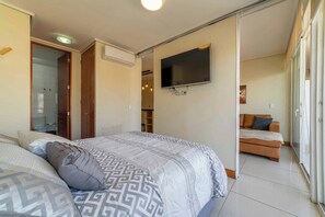 A bedroom with a bed, a television, a wardrobe, and a bathroom.