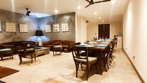 A dining area with a long table set for a meal, surrounded by wooden chairs and sofas. - Villa Reef Talpe (Unawatuna)
