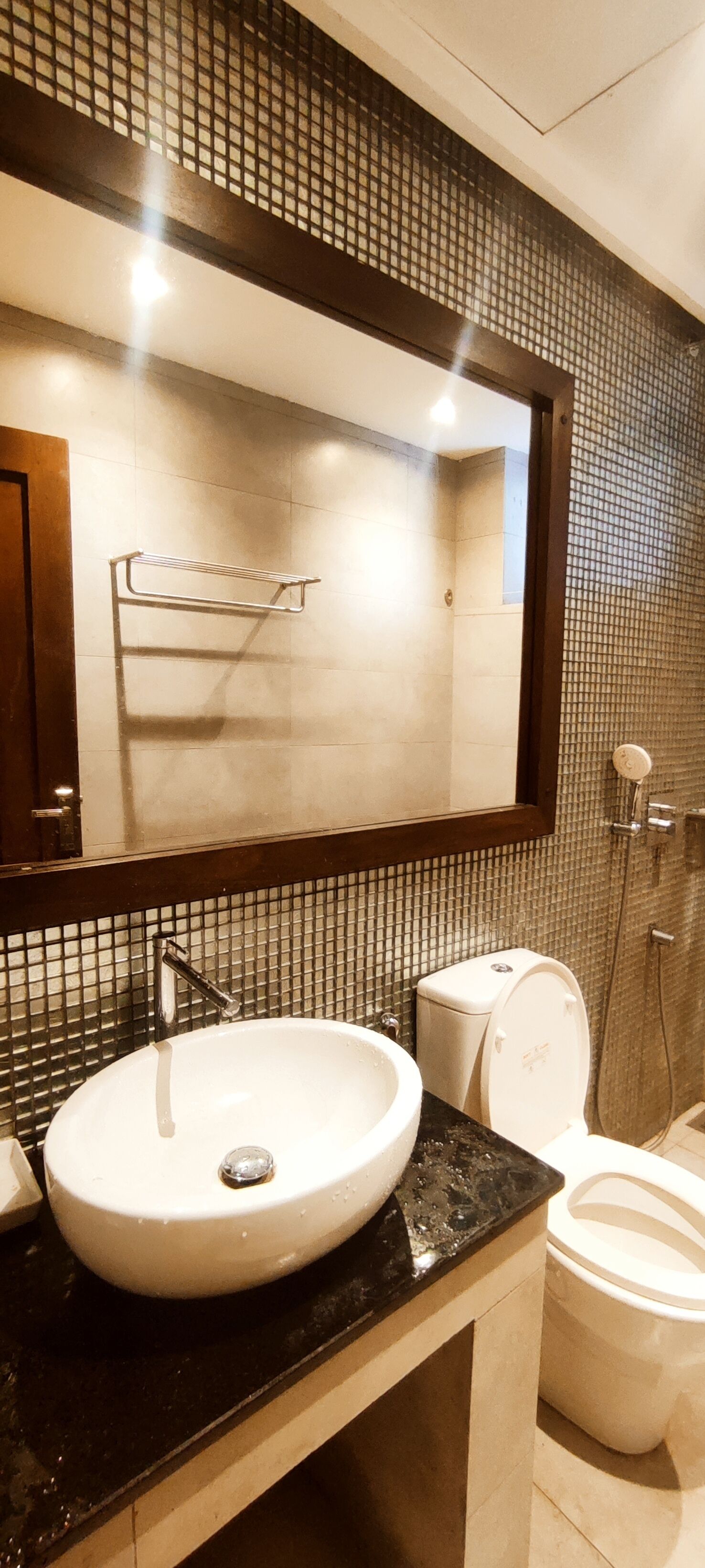 A bathroom with a large mirror, a sink, a toilet, and a shower.