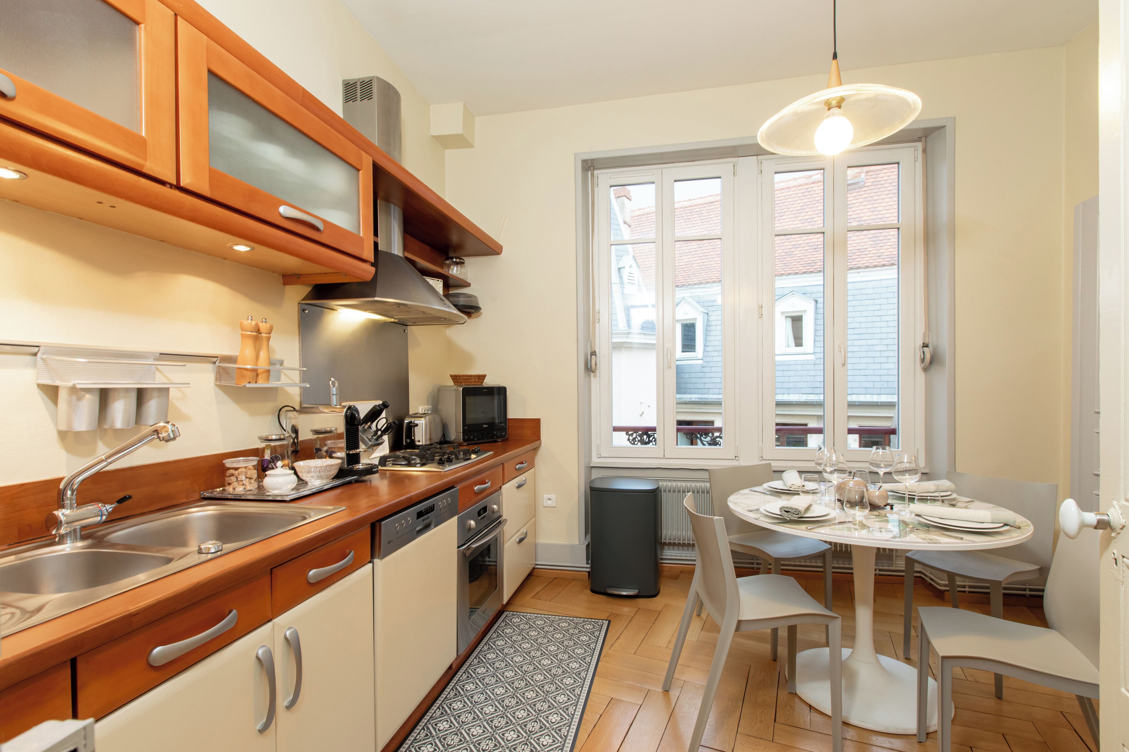 A compact kitchen with wooden cabinets, a sink, and a dining area with a table and chairs.