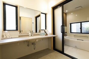 Une salle de bain moderne avec un grand miroir, une baignoire et un meuble-lavabo.