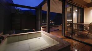 A modern outdoor hot tub area with a glass enclosure, a wooden deck, and a seating area with chairs. - Villa Otogibanashi (Kihoku)