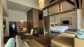 A modern hotel room with a sofa, a bed, a desk, and a television.