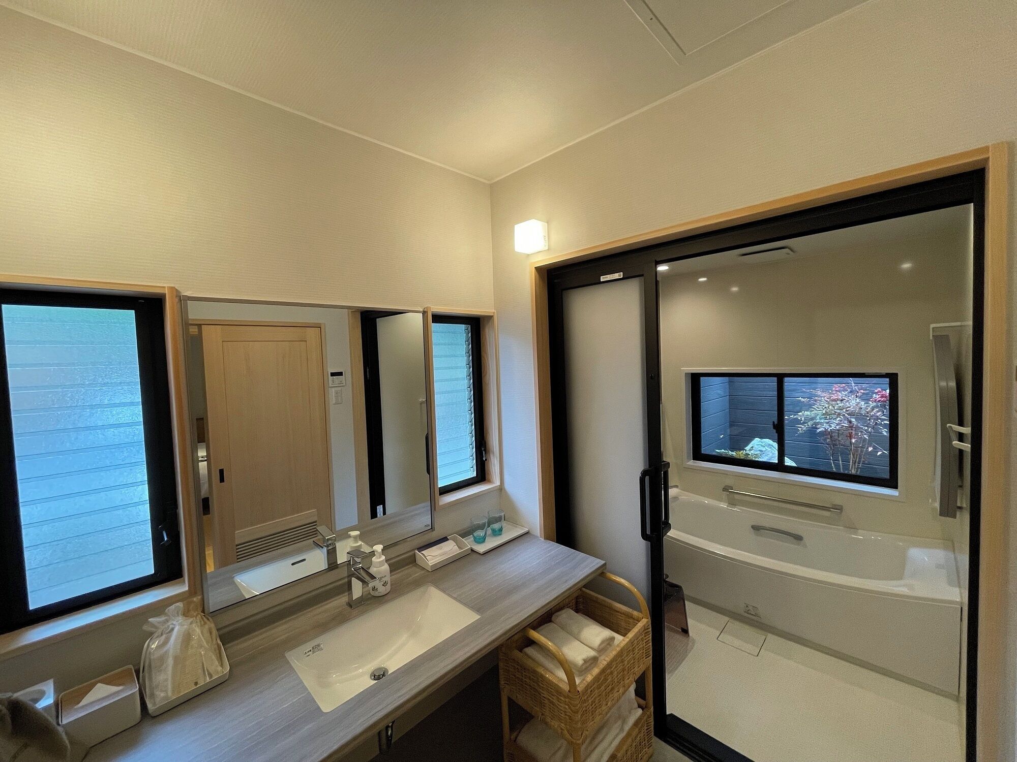 A modern bathroom with a large mirror, a sink, and a bathtub.