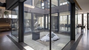 A modern interior with large glass walls, a central seating area with a snow-like feature, and a staircase leading to upper levels. - Meikeikyo Hanazono (Kutchan)