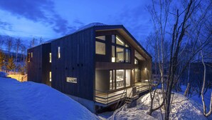 A modern wooden cabin with large windows, a balcony, and a snow-covered landscape. - Meikeikyo Hanazono (Kutchan)