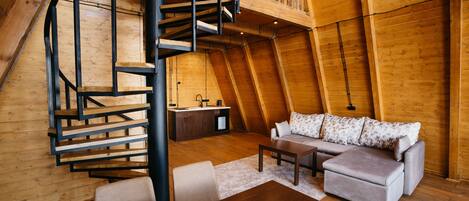Una stanza in stile loft con una scala a chiocciola, un divano, un tavolino da caffè e un angolo cottura.