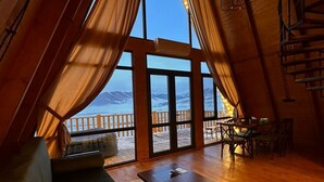 A cozy interior with a sofa, a table, and a view of the sea through large windows. - Chalet Myler (Yeghipatrush)