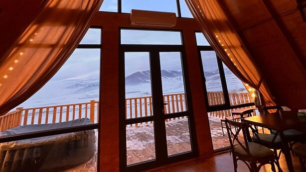 A cozy, triangular room with large windows offering a view of a snowy landscape. - Chalet Myler (Yeghipatrush)